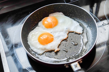 Two scrambled eggs in black frying pan