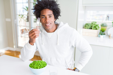 Fototapeta na wymiar African American man eating fresh green peas at home with a confident expression on smart face thinking serious