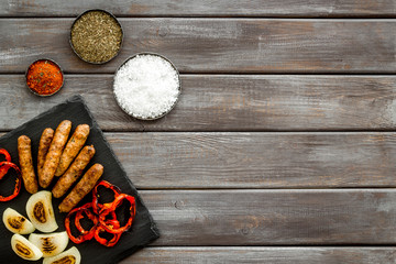 Obraz na płótnie Canvas Barbecue with sausages, vegetables on kitchen board and spices on wooden background top view copyspace
