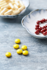 Vitamin C, Beta-Carotene tablets and Coenzyme Q10 capsules. Antioxidants. Concept for a healthy dietary supplementation. Bright wooden background. Close up. Copy space.  