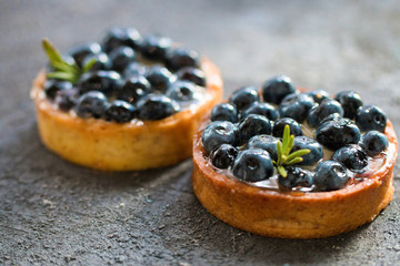 Delicious blueberry tartalets with vanilla cream on a grey background. Top view.