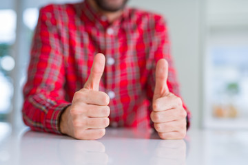 Close up of hands man doing thumbs up gesture over white table