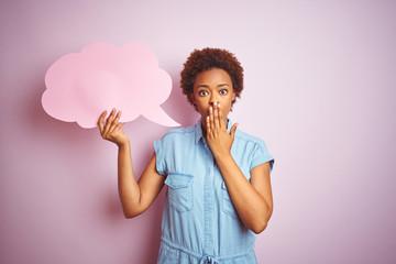 Young african american woman holding speech bubble over pink isolated background cover mouth with hand shocked with shame for mistake, expression of fear, scared in silence, secret concept