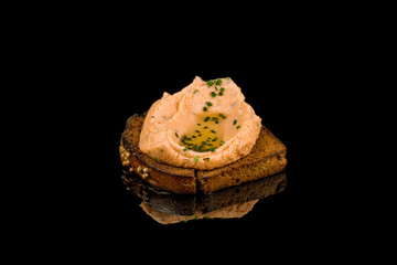 salmon pate on black bread on black glass with reflection