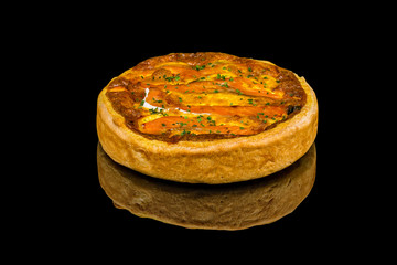 Quiche with salmon and spinach on black glass with reflection