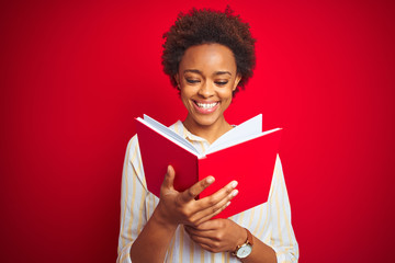 African american woman reading a book over red isolated background with a happy face standing and smiling with a confident smile showing teeth