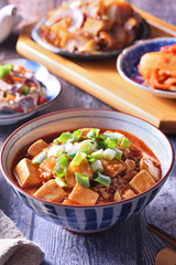 A bowl of rice with mapo doufu on a table                                                    
