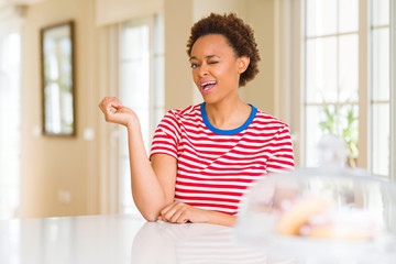 Young beautiful african american woman at home winking looking at the camera with sexy expression, cheerful and happy face.