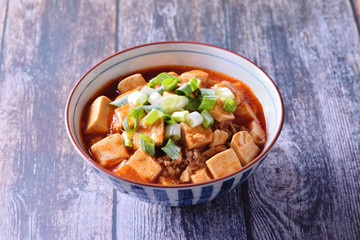 A bowl of rice with mapo doufu on a table                                                    
