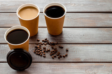 Caution: contents hot. Coffee to take away in paper cups with lids and beans on wooden table background mock up