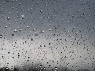 beautiful raindrops on the glass through which you can see the stormy gray sky