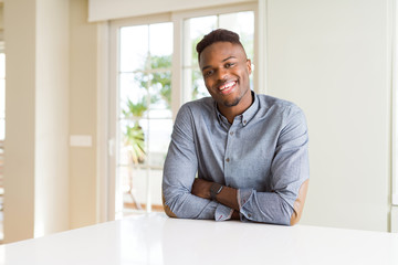 Naklejka premium Handsome african american man on white table happy face smiling with crossed arms looking at the camera. Positive person.