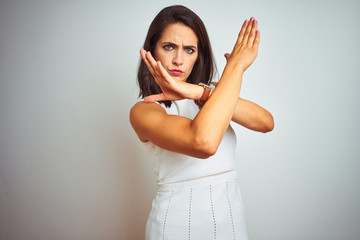Obraz premium Young beautiful woman wearing dress standing over white isolated background Rejection expression crossing arms doing negative sign, angry face