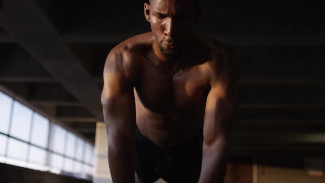 Athletic black male doing push ups in an urban setting, in slow motion 