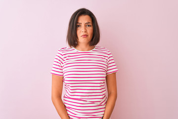 Young beautiful woman wearing striped t-shirt standing over isolated pink background depressed and worry for distress, crying angry and afraid. Sad expression.