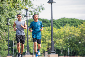 Young man and  elderly man running in the city. Healthy lifestyle concept. Young fitness man and  elderly man runner athlete running at park. Elderly sporty man running in morning workout.