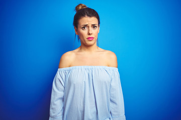 Fototapeta na wymiar Young beautiful woman wearing bun hairstyle over blue isolated background skeptic and nervous, frowning upset because of problem. Negative person.