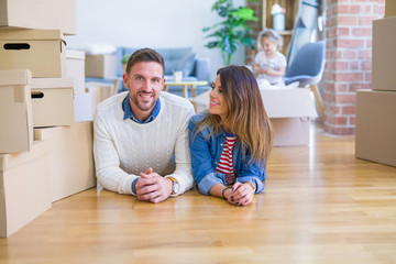 Beautiful famiily with kid lying down at new home around cardboard boxes