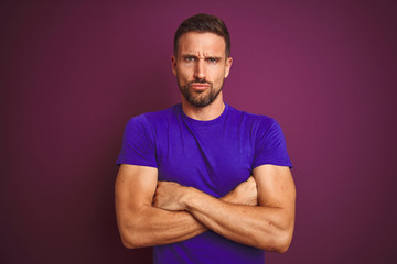 Young man wearing casual purple t-shirt over lilac isolated background skeptic and nervous, disapproving expression on face with crossed arms. Negative person.