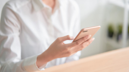 Close-up of hands using smartphone on wooden table and typing message to his friends.