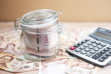 1000 Thai Baht banknote background and Money glass jar with Calculator. business, investment, retirement planning, finance and Saving for the future concepts