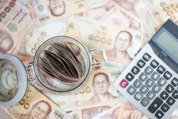 1000 Thai Baht banknote background and Money glass jar with Calculator. business, investment, retirement planning, finance and Saving for the future concepts