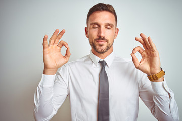 Young handsome business man wearing elegant white shirt over isolated background relax and smiling with eyes closed doing meditation gesture with fingers. Yoga concept.