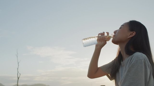 Asian girl sitting drinking  Bottled water in the middle of nature When the  sunlight, Sunset, On the weekend time