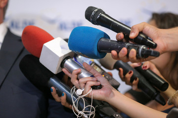Details with the hands of journalists holding microphones in fron of a politician during a press...