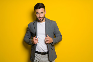 Young handsome man possing and modeling over yellow isolated background