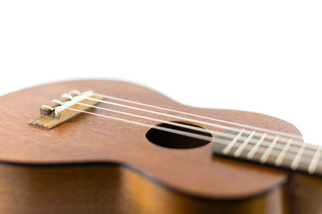 Fototapeta premium Close-up head of dark wooden ukulele music instrument Hawaiian guitar body with selected focus and copy space isolated over white background.