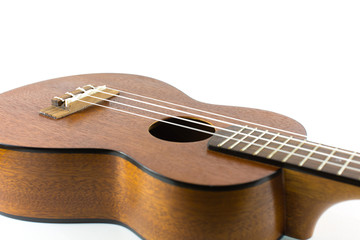 Close-up head of dark wooden ukulele music instrument Hawaiian guitar body with selected focus and copy space isolated over white background.