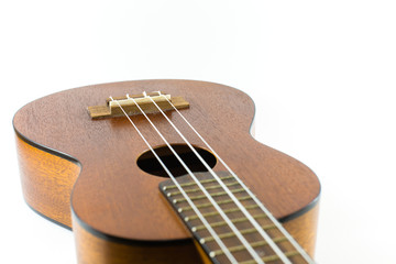 Obraz premium Close-up head of dark wooden ukulele music instrument Hawaiian guitar body with selected focus and copy space isolated over white background.