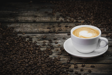 cup of coffee latte with beans on brown wooden background 