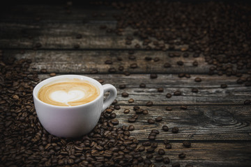 cup of coffee latte with beans on brown wooden background 