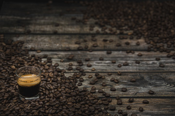 glass of coffee espresso shot with beans on brown wooden background 