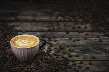 cup of coffee latte with beans on brown wooden background 