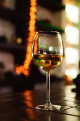 Glass of white wine on background of colorful bar. Bokeh. Warm toning. Space for text. Concept alcoholic drinks. 