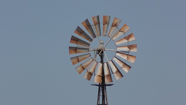 Close up of Iconic spinning wind mill in outback Australia, with sunny blue sky as background.
