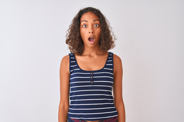 Young brazilian woman wearing striped t-shirt standing over isolated white background afraid and shocked with surprise expression, fear and excited face.