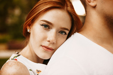 Close up portrait of a charming red hair woman with freckles and grey eyes looking at camera...
