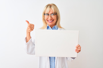 Naklejka premium Middle age scientist woman wearing glasses holding banner over isolated white background happy with big smile doing ok sign, thumb up with fingers, excellent sign