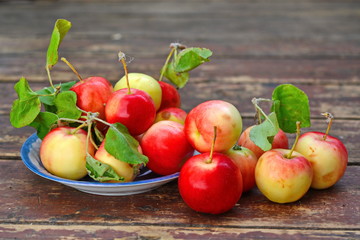 red yellow apples with green foliage in blue saucer and scattered around it on old wooden plank surface