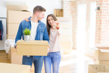 Beautiful young couple hugging in love and showing keys of new house, smiling happy moving to a new apartment