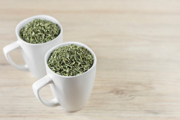 white cup with moringa leaves on wooden background