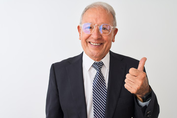 Senior grey-haired businessman wearing suit and glasses over isolated white background doing happy thumbs up gesture with hand. Approving expression looking at the camera with showing success.