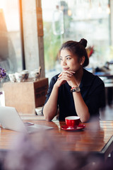 Asian woman working in cafe and looking out window..