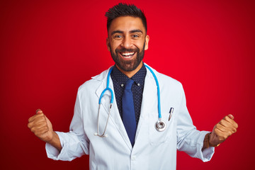 Young indian doctor man wearing stethoscope standing over isolated red background celebrating...