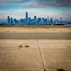 San Francisco skyline with old cracked pavement in foreground with a few weeds growing in the cracks