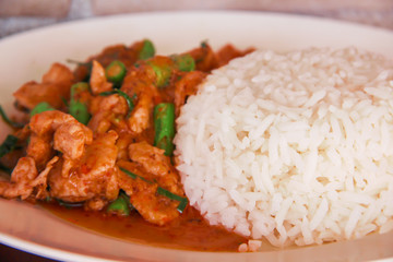 Close up stir fried pork with red curry paste and organic green bean in white plated , Thai food background